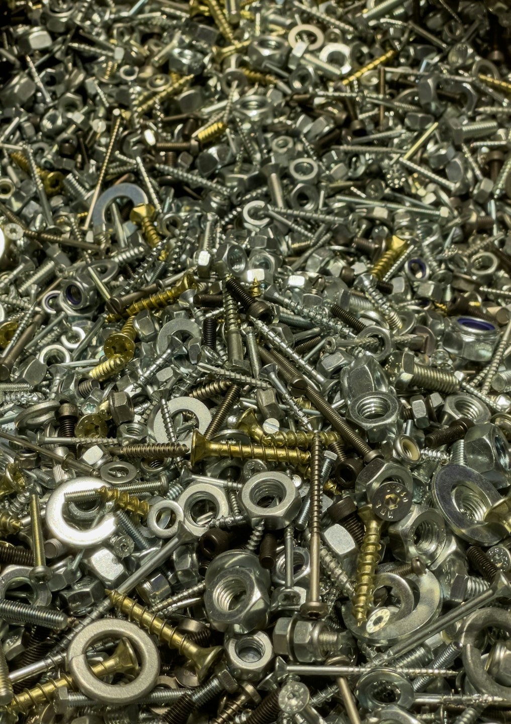 Segamini kuhjatud metallmutrid ja -kruvid.